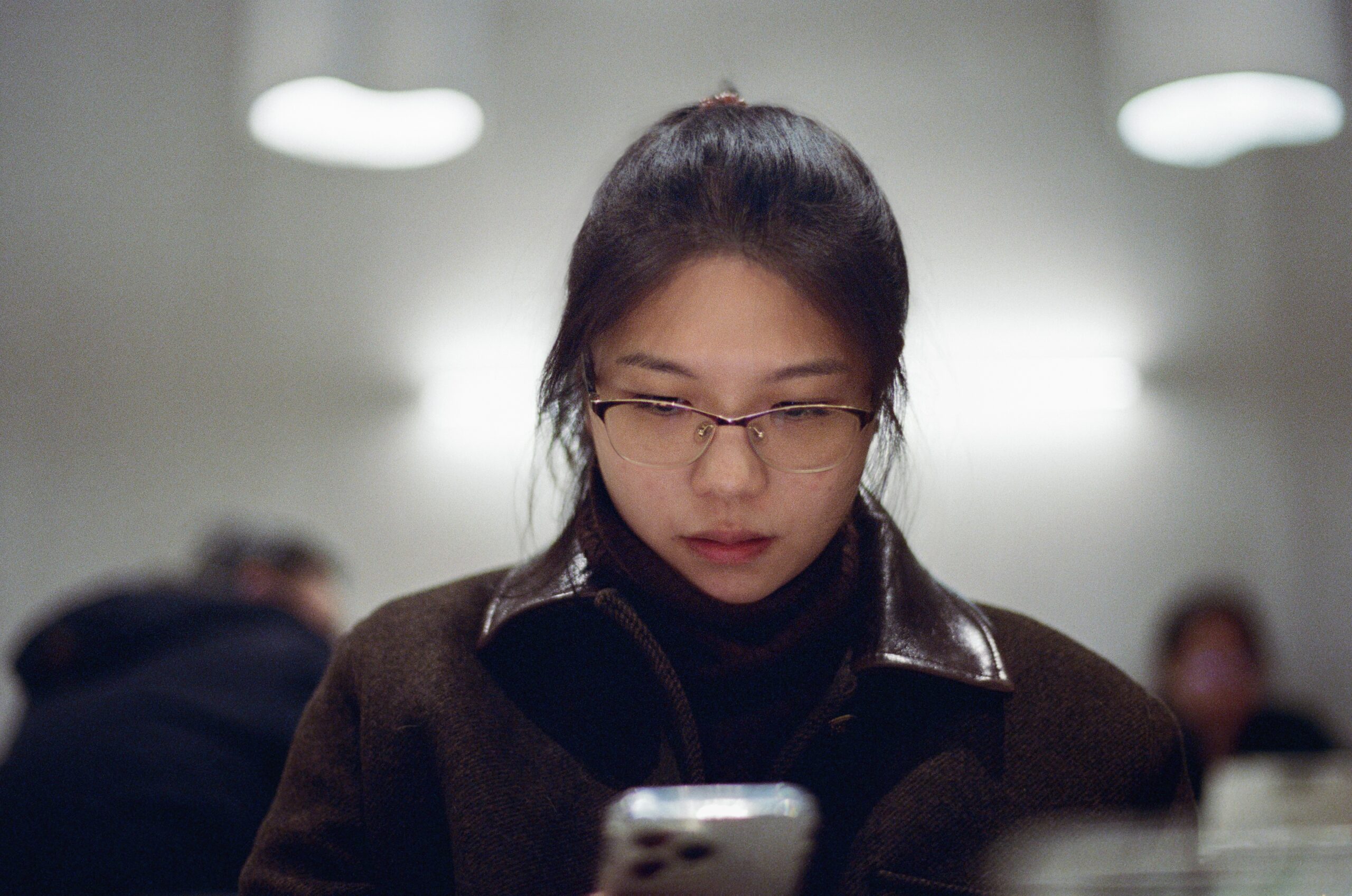Person holding phone with frustrated expression, surrounded by documents