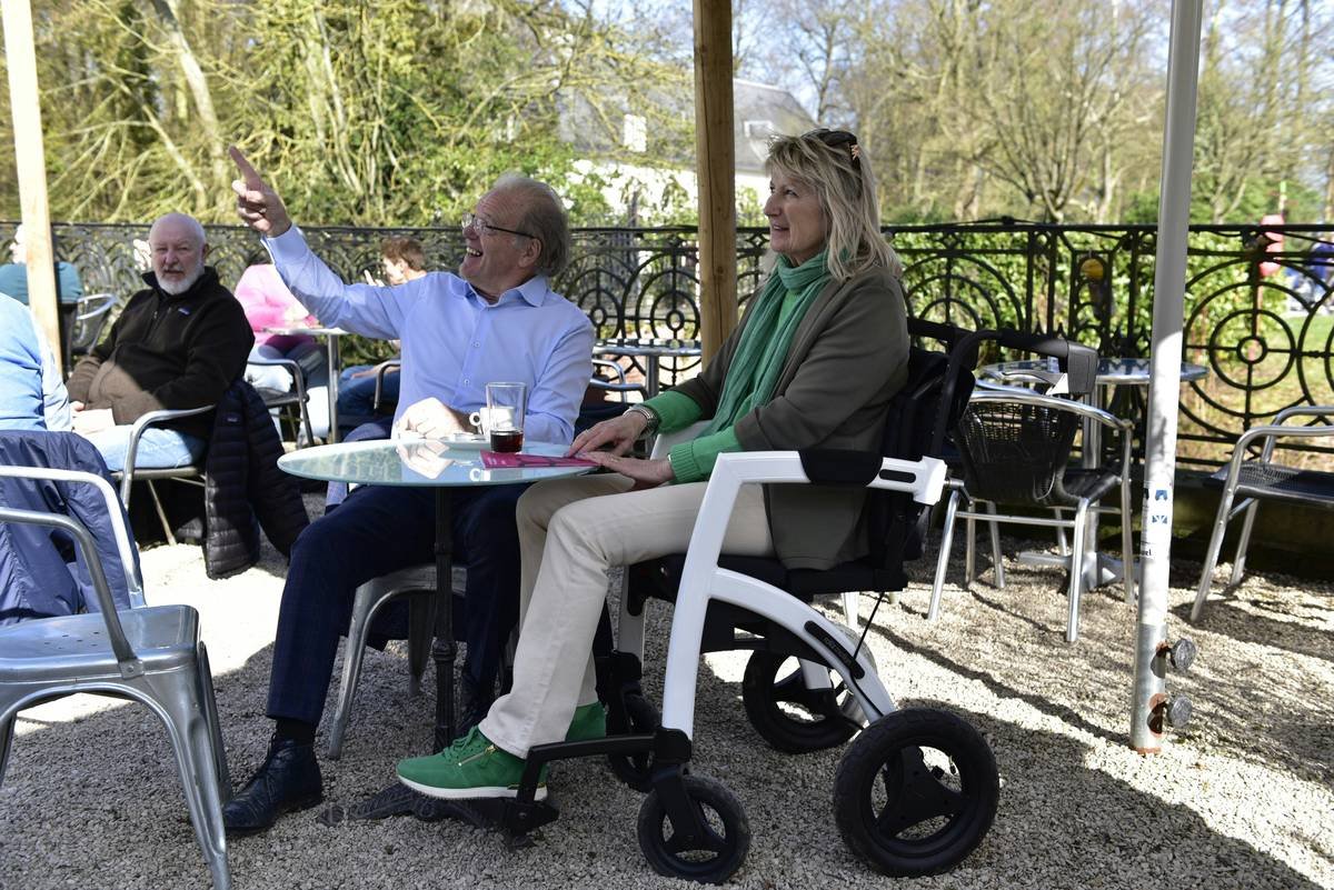 Elderly couple enjoying being outside with a wheelchair.