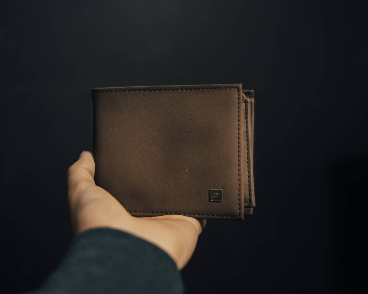 person holding brown leather bifold wallet